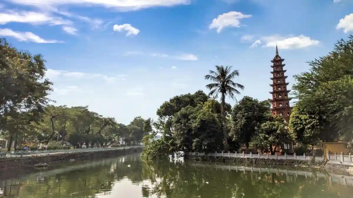 Tran Quoc Pagoda in Hanoi, Vietnam. The pagoda is situated in the trees beside a river with blue skies and clouds overhead. Tran Quoc Pagoda in Hanoi, Vietnam. The pagoda is situated in the trees beside a river with blue skies and clouds overhead.