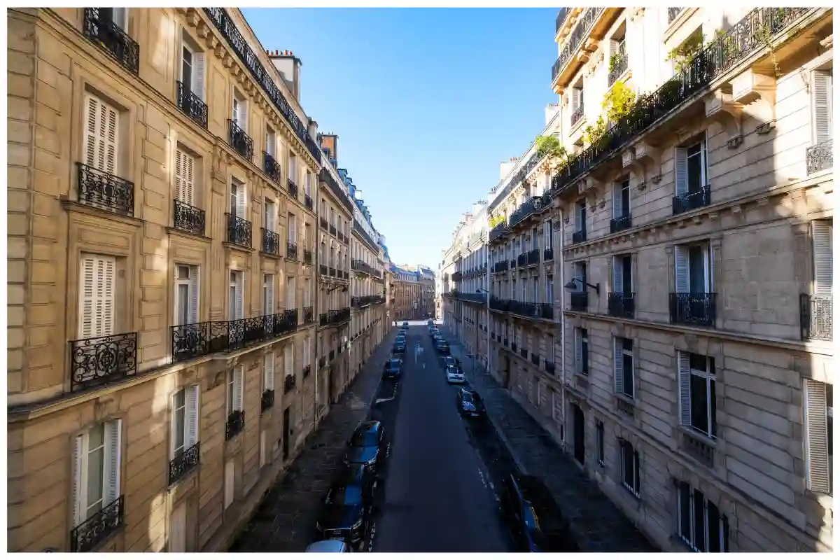 Symmetrical Haussmannian buildings with ornate facades, balconies, and Parisian windows lining a wide boulevard. Symmetrical Haussmannian buildings with ornate facades, balconies, and Parisian windows lining a wide boulevard.