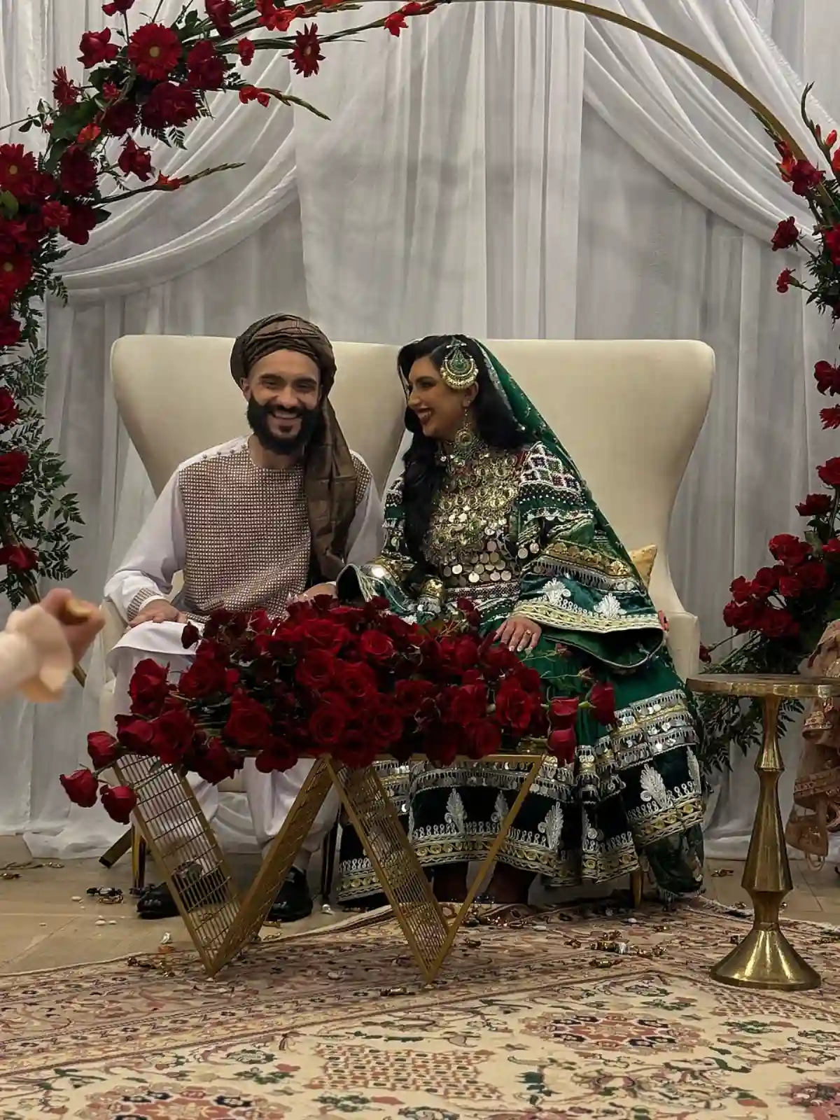 Afghan bride and groom in traditional attire, with the bride wearing a vibrant dress adorned with intricate embroidery and the groom in a formal sherwani, showcasing Afghan cultural elegance. Afghan bride and groom in traditional attire, with the bride wearing a vibrant dress adorned with intricate embroidery and the groom in a formal sherwani, showcasing Afghan cultural elegance.