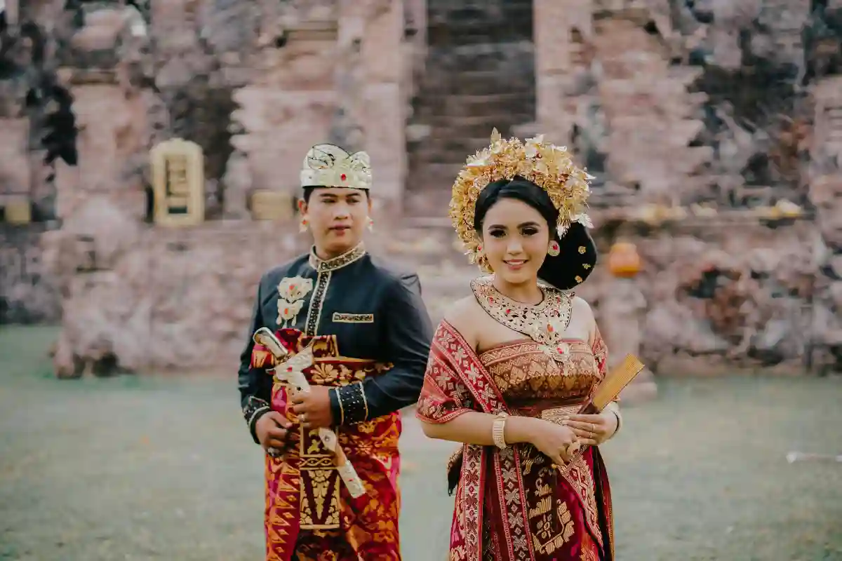 Newlyweds in traditional Balinese outfits, with the bride wearing an elaborate golden headdress and the groom in a ceremonial shirt and songket sarong, capturing the beauty and elegance of a Balinese wedding. Newlyweds in traditional Balinese outfits, with the bride wearing an elaborate golden headdress and the groom in a ceremonial shirt and songket sarong, capturing the beauty and elegance of a Balinese wedding.