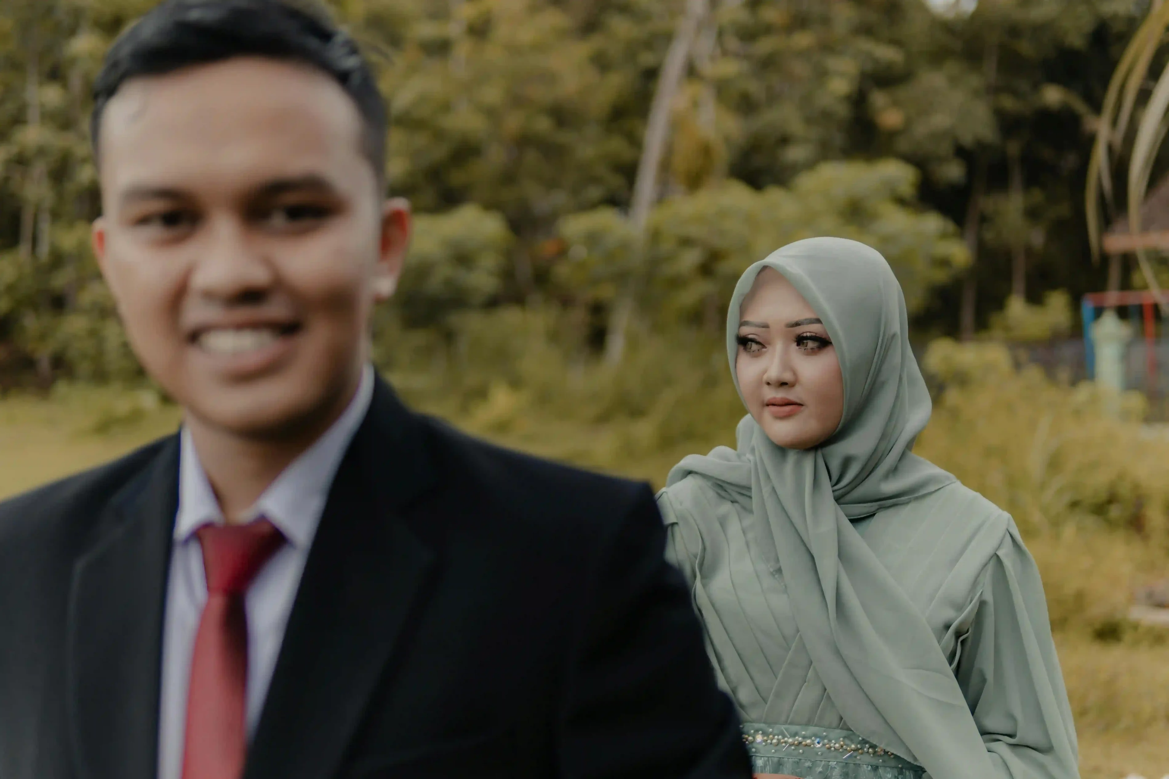 A woman in traditional attire, in focus, with a blurred man in the background, capturing a moment of daily life in East Java. A woman in traditional attire, in focus, with a blurred man in the background, capturing a moment of daily life in East Java.