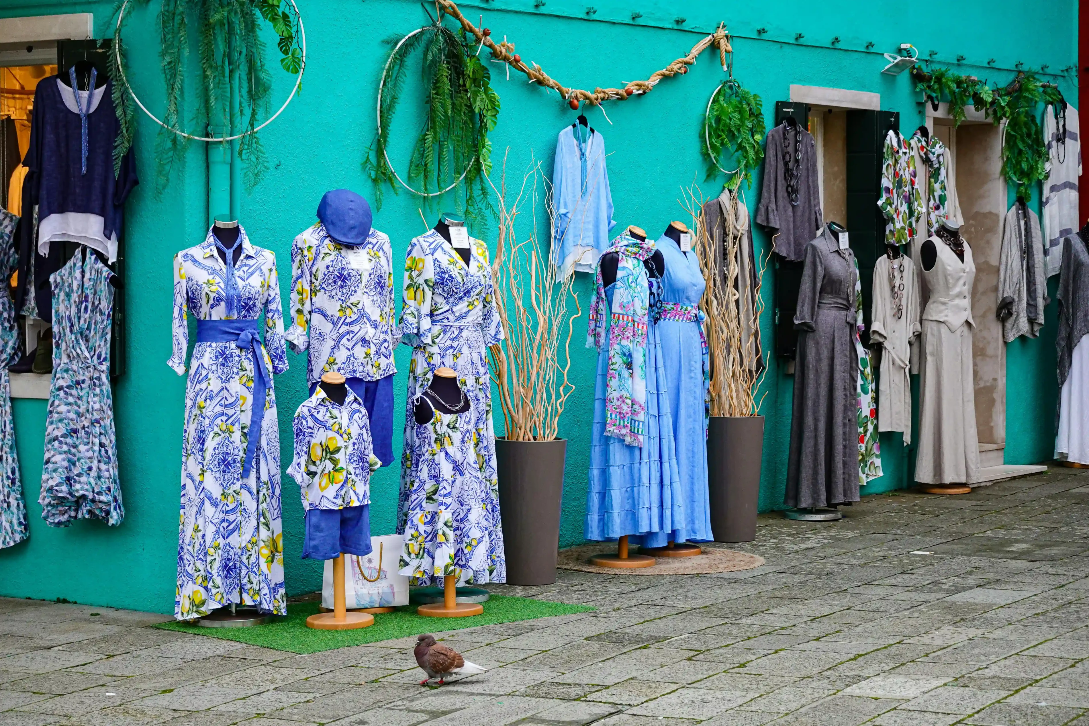 A vibrant storefront showcasing elegant Italian designer dresses with colorful displays and stylish window arrangements.