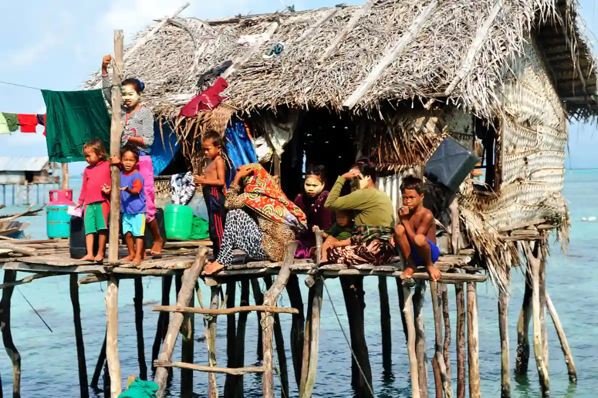 A vibrant view of a Sama-Bajau village, with stilt houses over clear turquoise waters, surrounded by boats and tropical greenery. A vibrant view of a Sama-Bajau village, with stilt houses over clear turquoise waters, surrounded by boats and tropical greenery.
