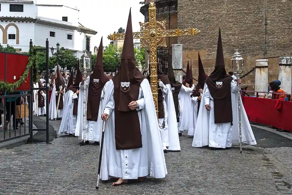 Procession during Semana Santa with participants dressed in traditional robes and carrying religious icons through the streets. Procession during Semana Santa with participants dressed in traditional robes and carrying religious icons through the streets.