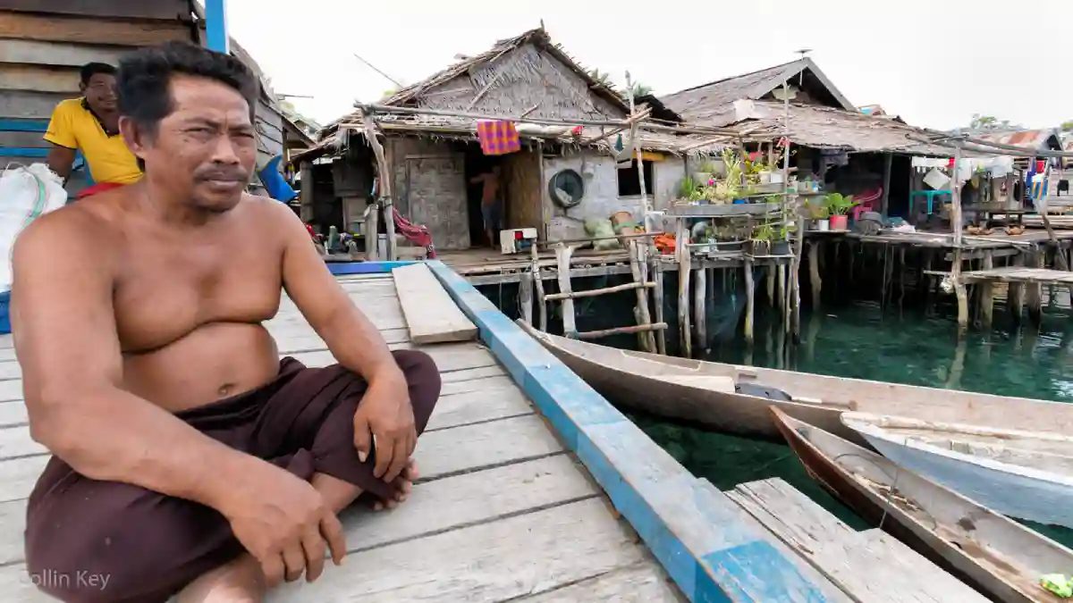 A dignified Bajau chief in traditional attire, standing proudly with his community in the background, embodying the leadership and heritage of the Bajau people. A dignified Bajau chief in traditional attire, standing proudly with his community in the background, embodying the leadership and heritage of the Bajau people.