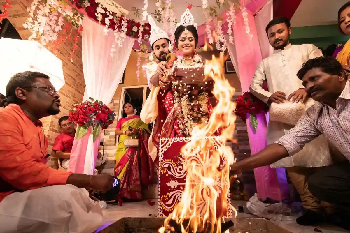 The bride and groom performing sacred rituals during a traditional Bengali wedding ceremony. The bride and groom performing sacred rituals during a traditional Bengali wedding ceremony.