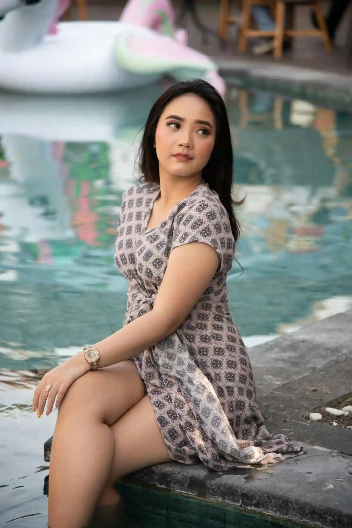 A woman in a mini dress sits by a fountain in Bali, enjoying the serene atmosphere of the tropical paradise. A woman in a mini dress sits by a fountain in Bali, enjoying the serene atmosphere of the tropical paradise.