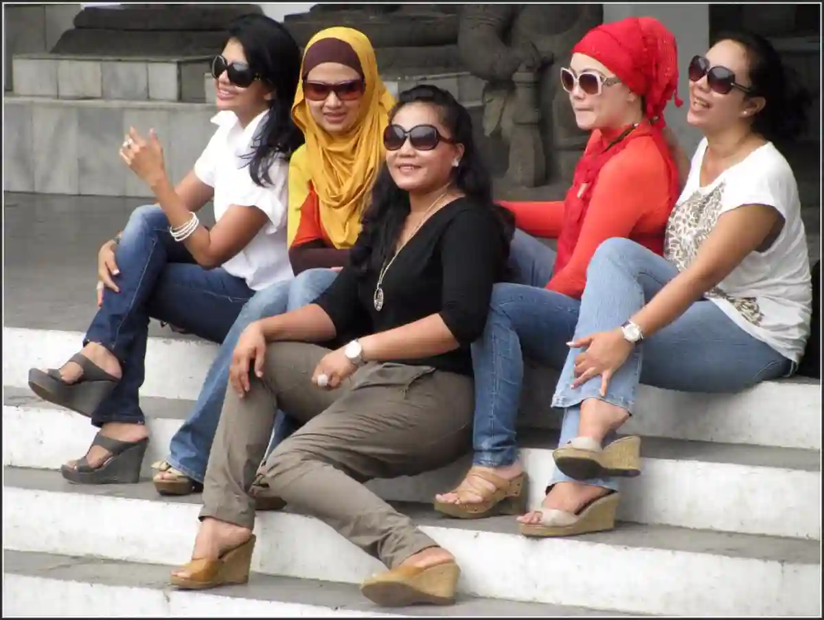 Indonesian women dressed in casual, modern outfits, enjoying a sunny day in an urban or rural setting. Indonesian women dressed in casual, modern outfits, enjoying a sunny day in an urban or rural setting.
