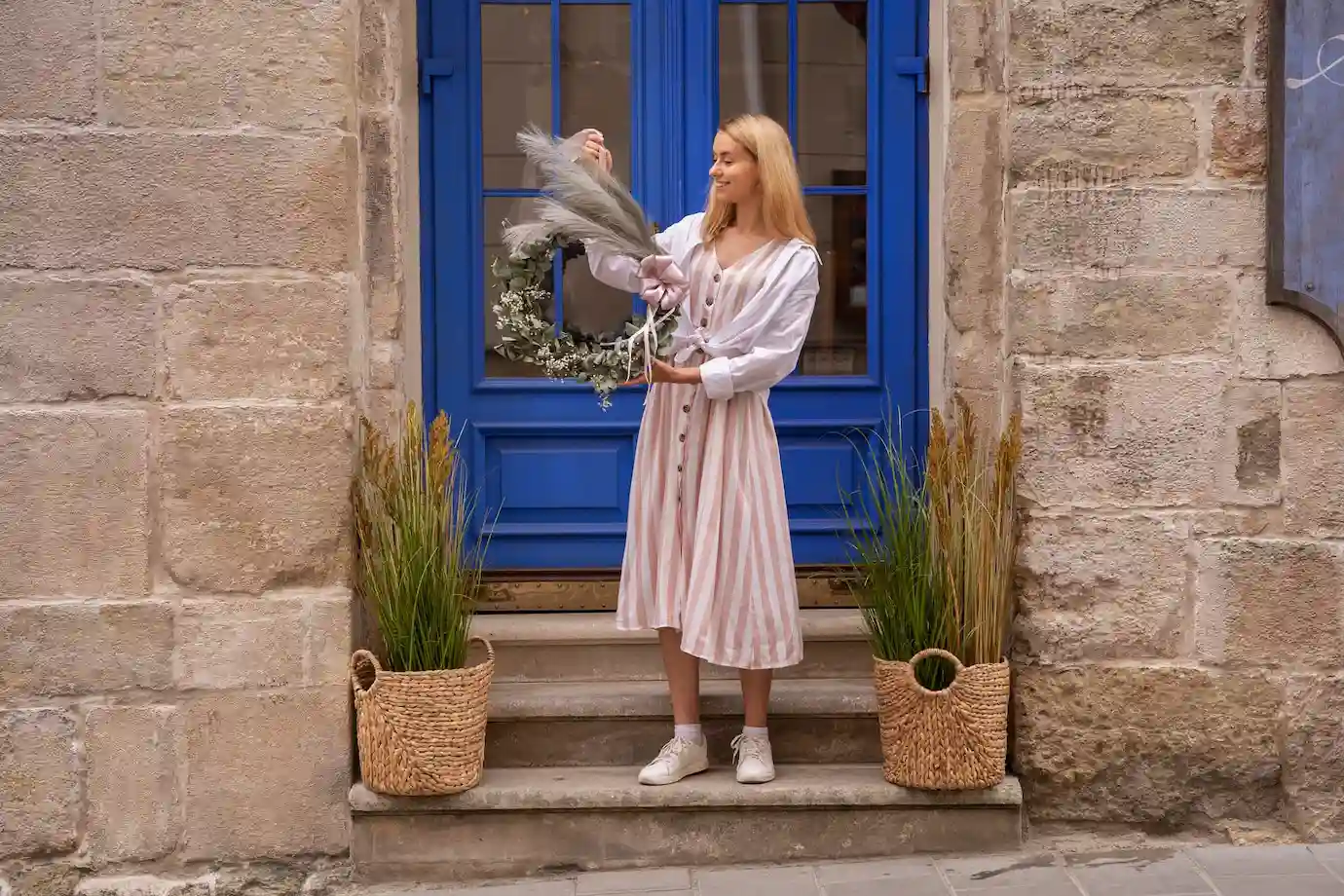 Person decorating their front door with flowers and festive ornaments, adding a personal touch to their home. Person decorating their front door with flowers and festive ornaments, adding a personal touch to their home.