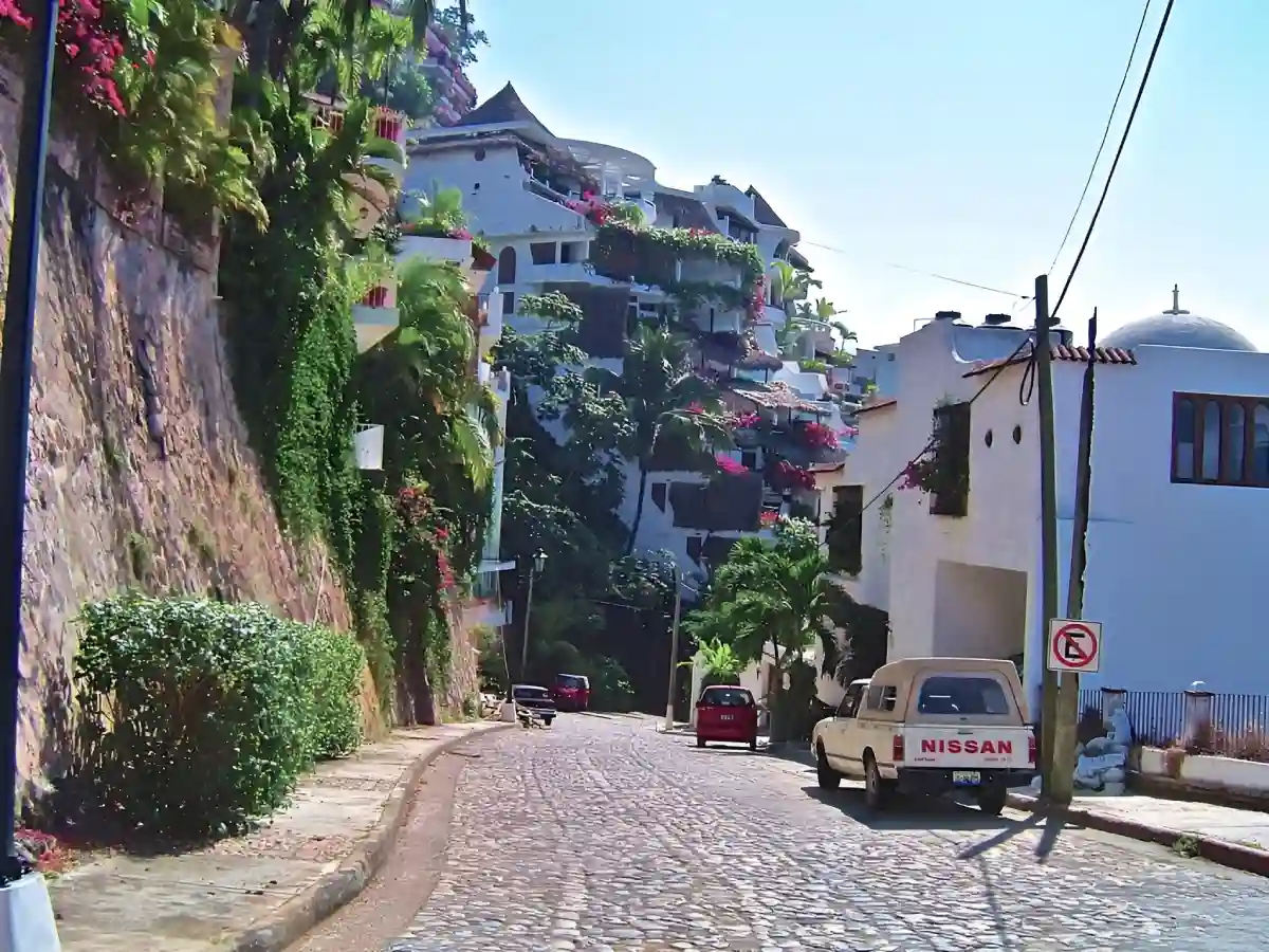 A quiet, cobblestone alley in Puerto Vallarta leading toward the lush, green mountains in the distance. A quiet, cobblestone alley in Puerto Vallarta leading toward the lush, green mountains in the distance.