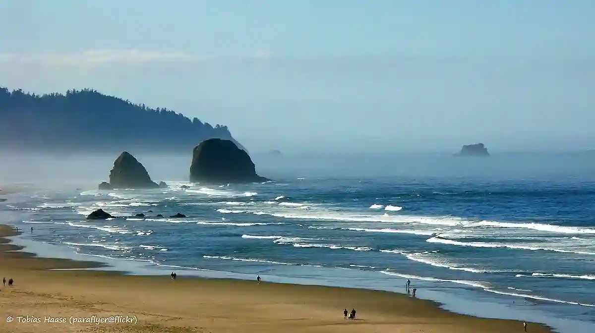 The iconic Haystack Rock towering over the sandy shores of Cannon Beach, Oregon, with the Pacific Ocean gently rolling in. The iconic Haystack Rock towering over the sandy shores of Cannon Beach, Oregon, with the Pacific Ocean gently rolling in.