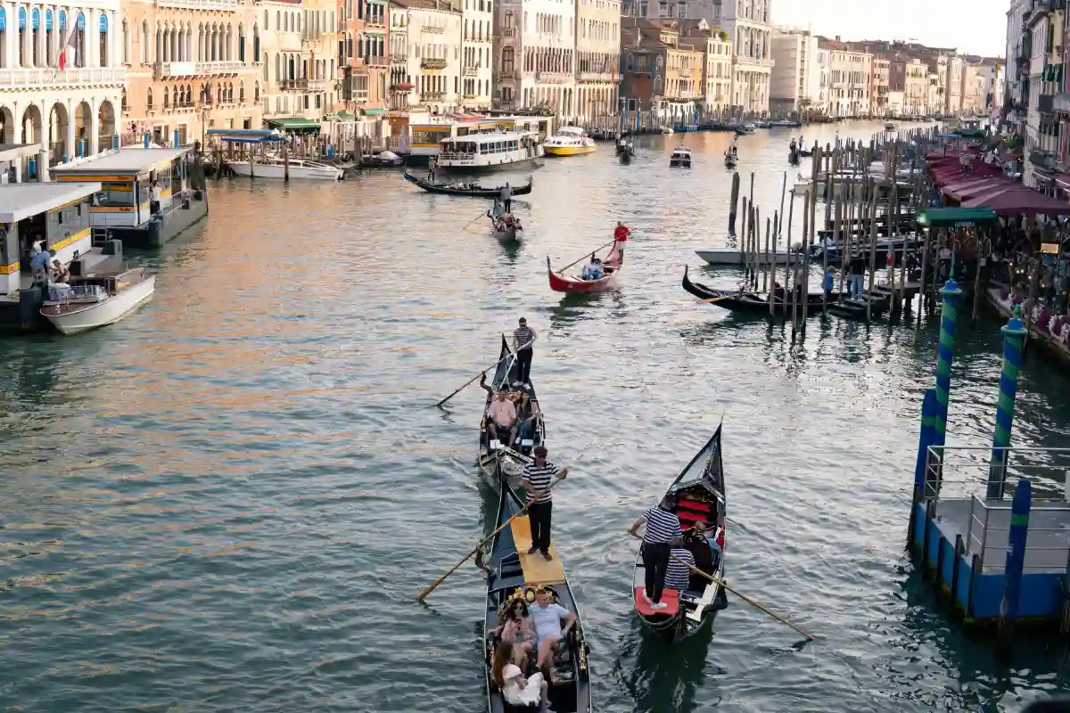 Tourists enjoying a serene gondola ride along the Grand Canal in Venice, surrounded by historic buildings and picturesque views. Tourists enjoying a serene gondola ride along the Grand Canal in Venice, surrounded by historic buildings and picturesque views.
