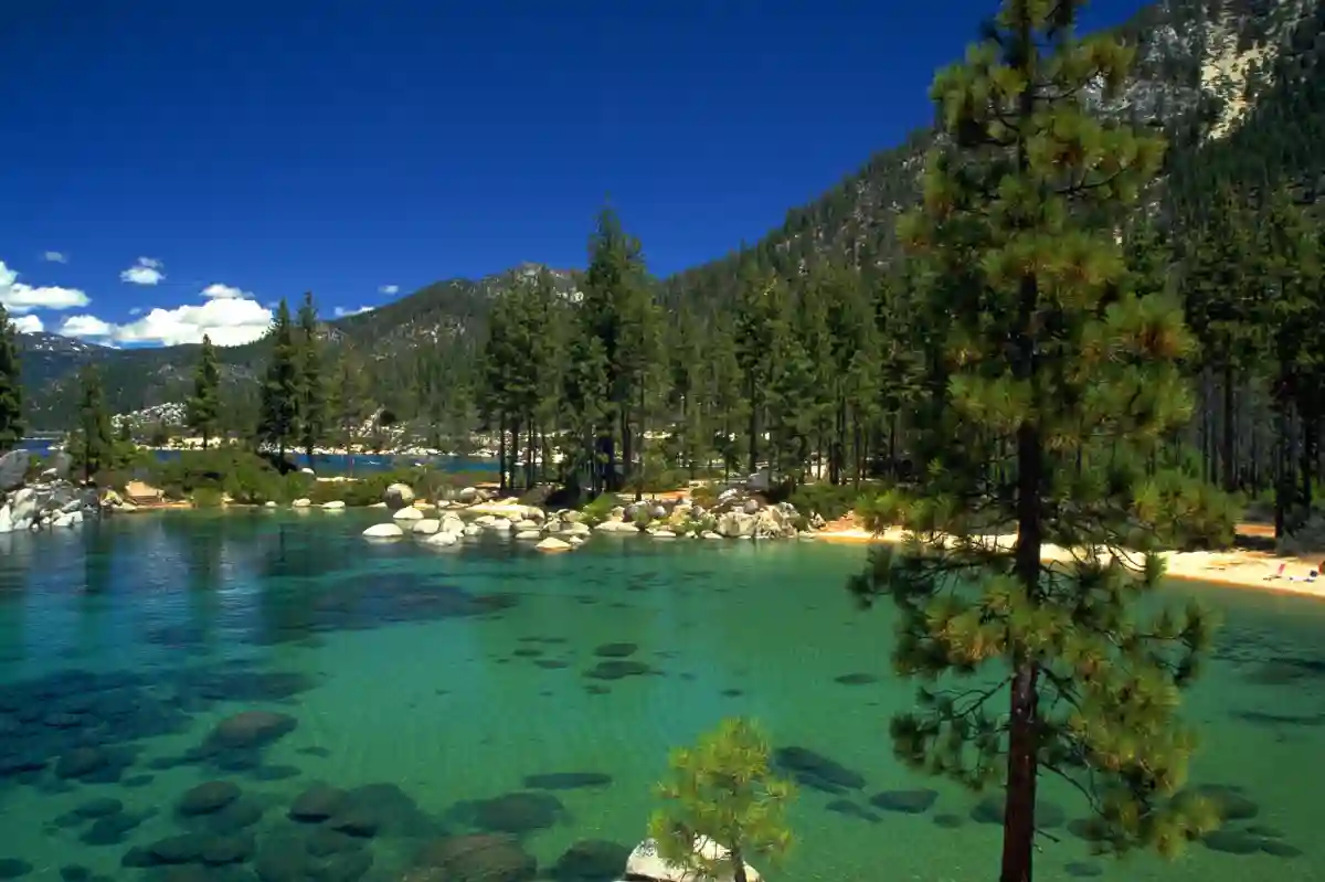 Crystal-clear waters of Lake Tahoe surrounded by majestic mountains, with people enjoying outdoor activities on a sunny August day. Crystal-clear waters of Lake Tahoe surrounded by majestic mountains, with people enjoying outdoor activities on a sunny August day.