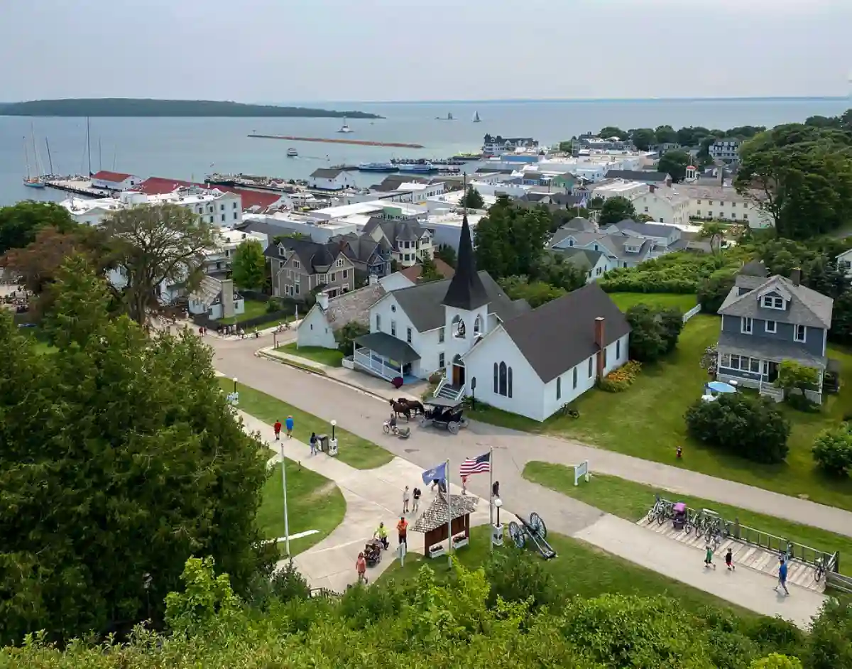 A scenic view of Mackinac Island, featuring historic architecture, lush greenery, and the iconic Mackinac Bridge in the background. A scenic view of Mackinac Island, featuring historic architecture, lush greenery, and the iconic Mackinac Bridge in the background.