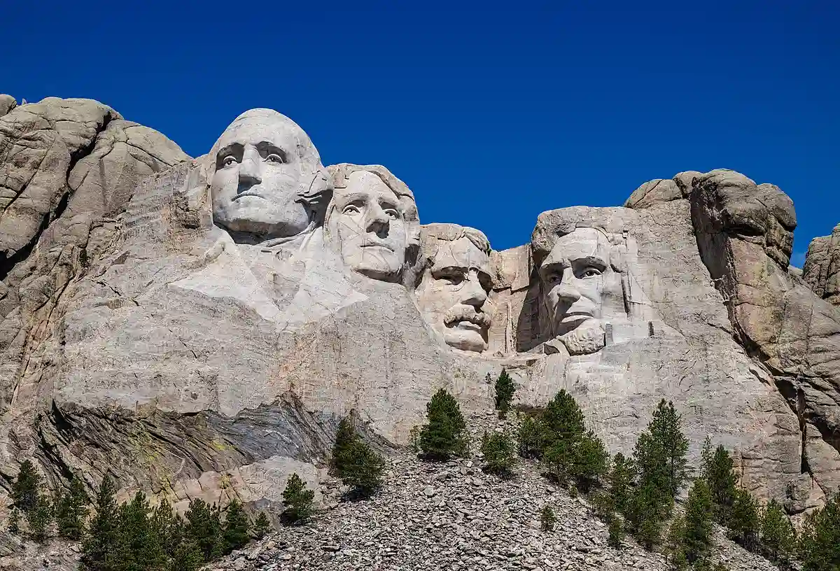 The iconic faces of Mount Rushmore carved into granite, set against the backdrop of the Black Hills and a clear summer sky. The iconic faces of Mount Rushmore carved into granite, set against the backdrop of the Black Hills and a clear summer sky.
