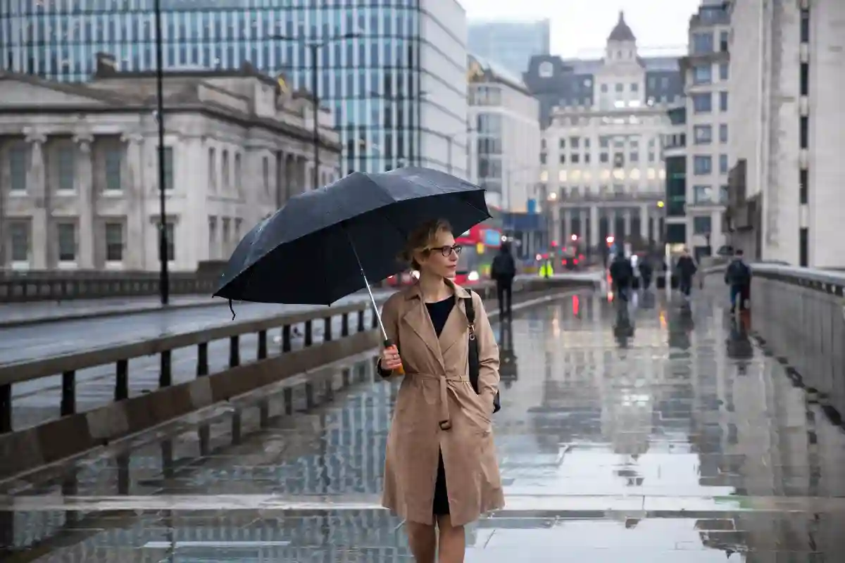A woman walking through a city street with an umbrella, enjoying the rain while exploring the urban scene. A woman walking through a city street with an umbrella, enjoying the rain while exploring the urban scene.
