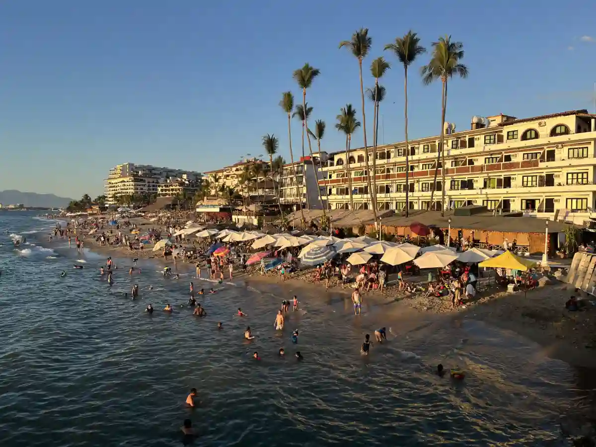 People enjoying the sandy beaches and turquoise waters of Puerto Vallarta, with some swimming and others lounging in the sun. People enjoying the sandy beaches and turquoise waters of Puerto Vallarta, with some swimming and others lounging in the sun.