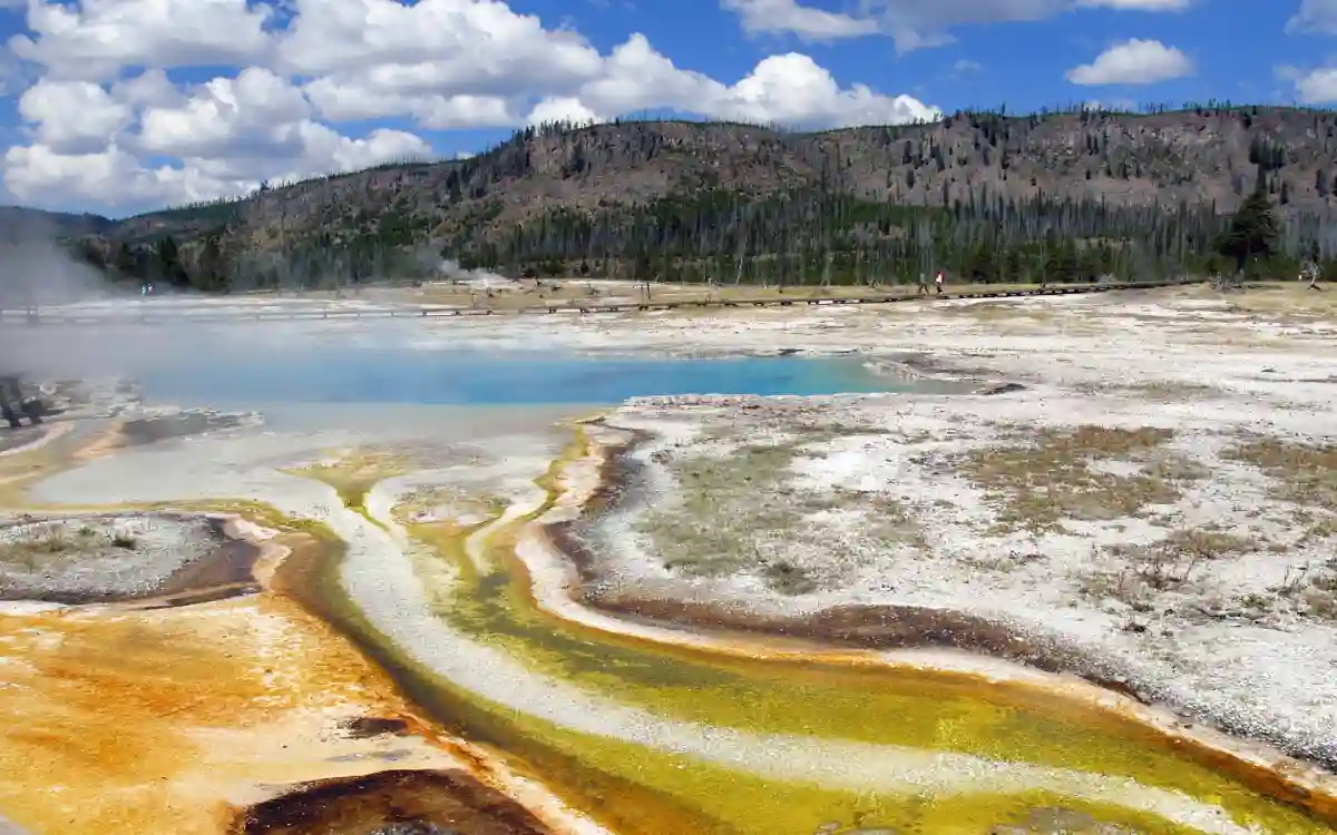 The striking yellow, white, and blue hues of a geothermal hot spring in Yellowstone National Park, surrounded by steam and rocky formations. The striking yellow, white, and blue hues of a geothermal hot spring in Yellowstone National Park, surrounded by steam and rocky formations.