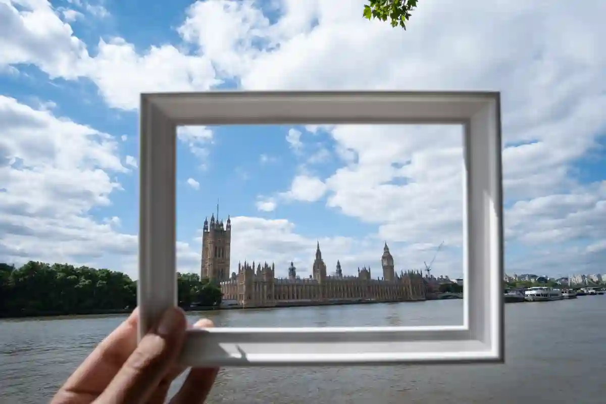 A person holding a photo frame in front of a famous landmark, framing the scene as if it were a photo. A person holding a photo frame in front of a famous landmark, framing the scene as if it were a photo.