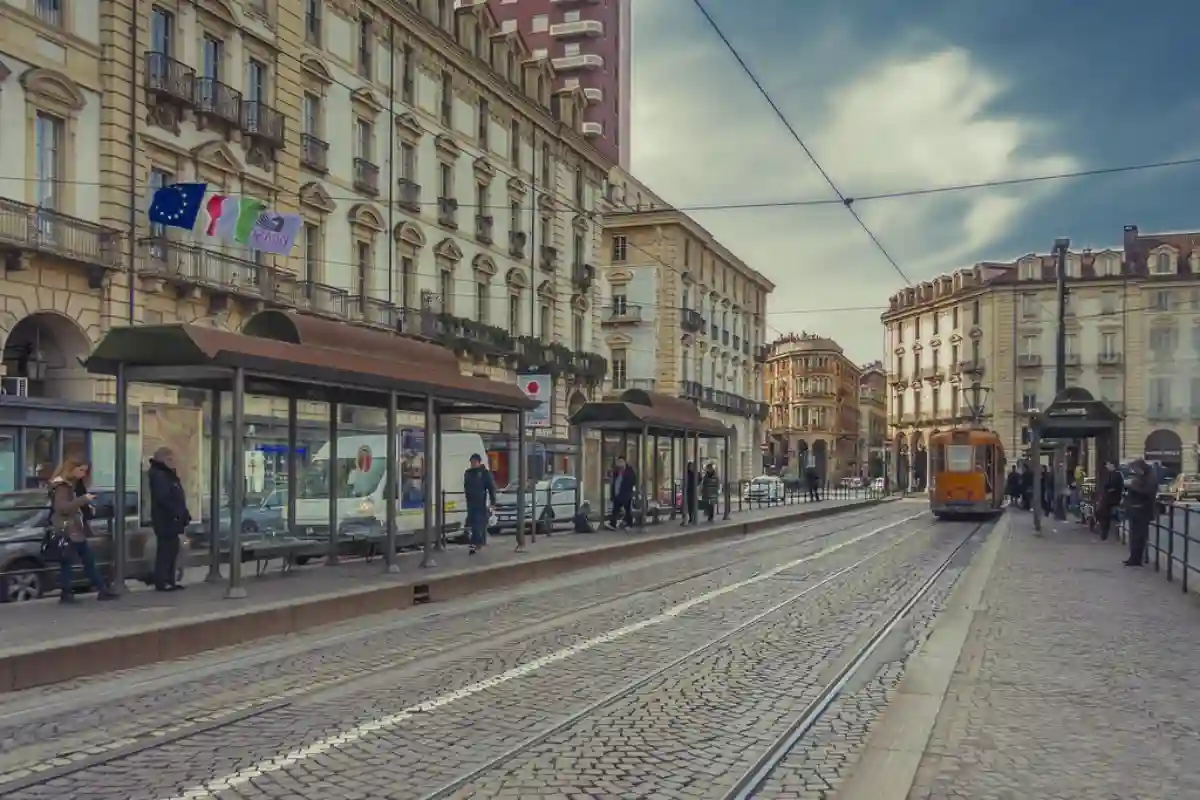 Tourists walking through Piazza Castello in Torino, surrounded by historic buildings and lively cafes. Tourists walking through Piazza Castello in Torino, surrounded by historic buildings and lively cafes.