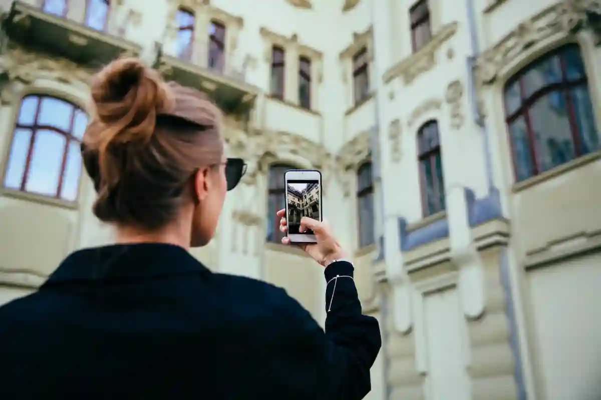 A fashionable woman taking a photo of an old, historic building with a modern camera in hand. A fashionable woman taking a photo of an old, historic building with a modern camera in hand.