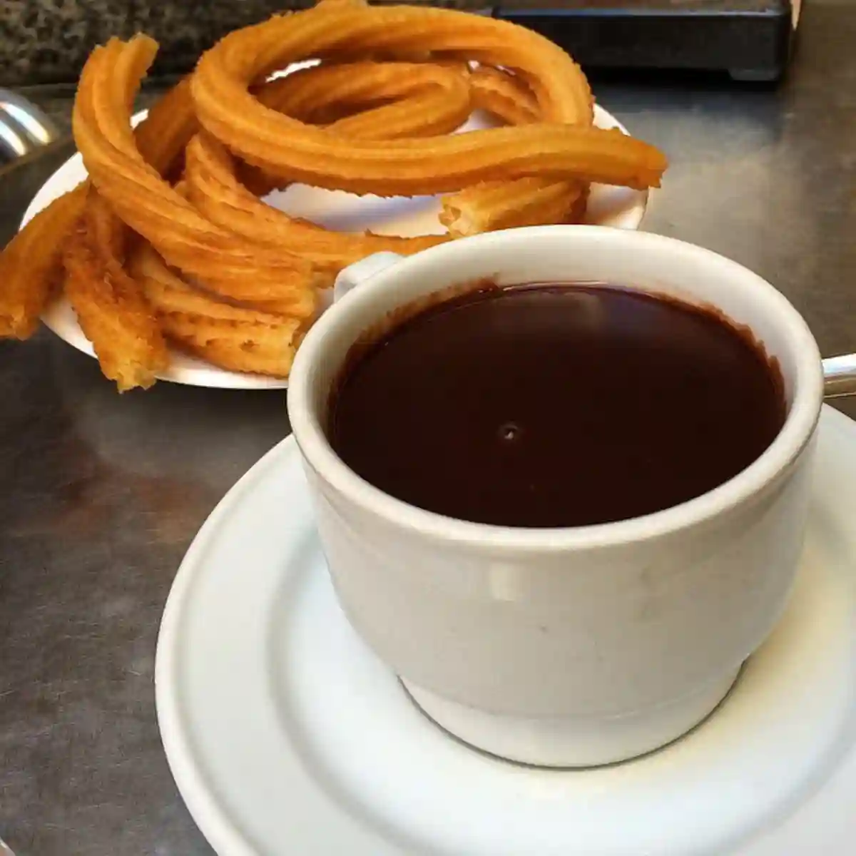 Classic scene at San GinƩs, one of the oldest and most famous spots for chocolate con churros in Madrid, with warm churros and rich chocolate served to visitors. Classic scene at San GinƩs, one of the oldest and most famous spots for chocolate con churros in Madrid, with warm churros and rich chocolate served to visitors.